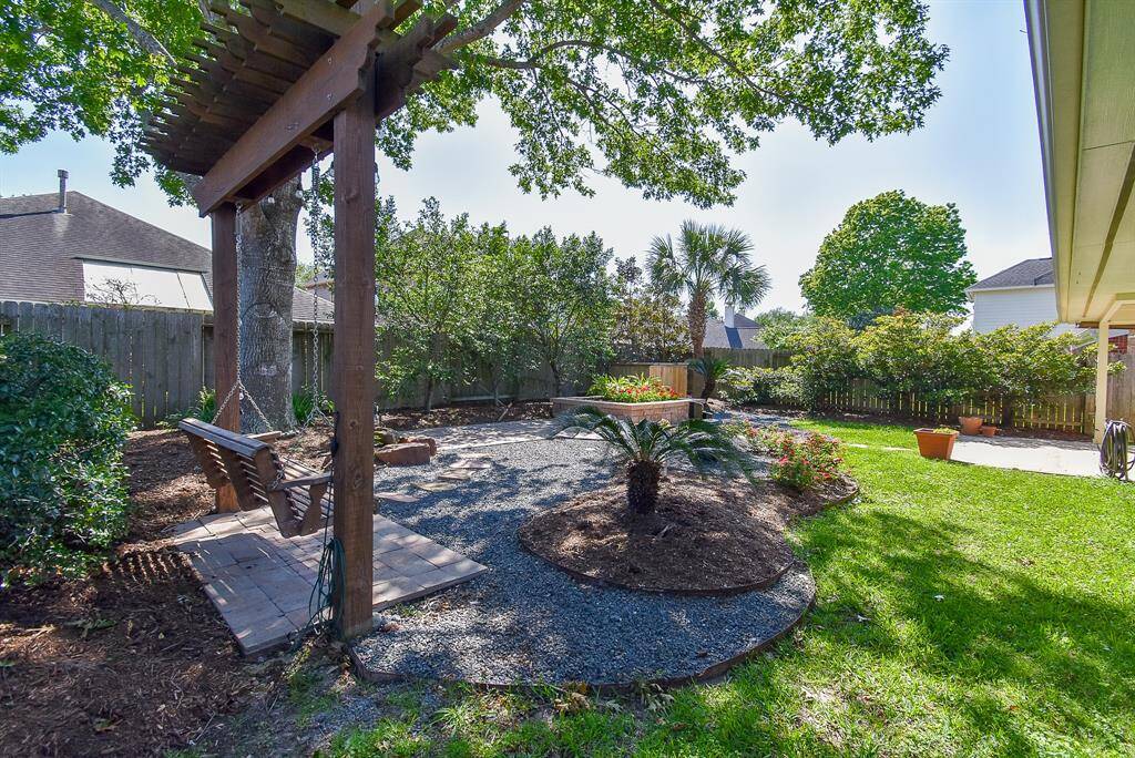Arguably the best feature of the home, the backyard is a serene, beautifully landscaped retreat. Enjoy the soothing sounds of a custom water feature, relax under the pergola on a swing, and take in the beauty of mature trees, vibrant flowers, and lush greenery.