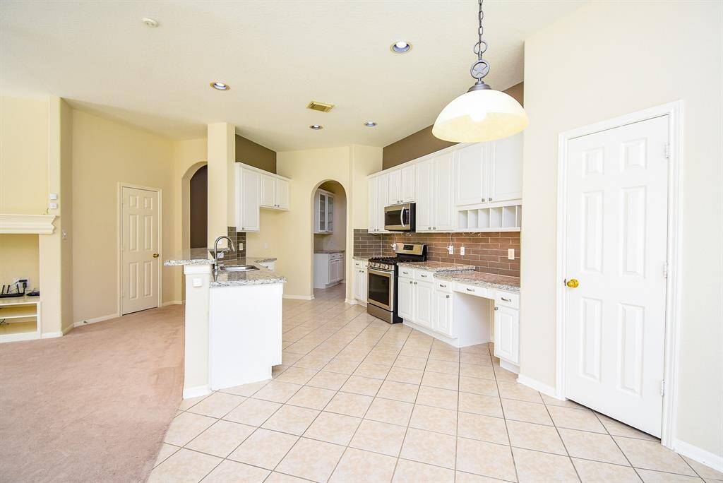The modern kitchen is the heart of the home, featuring granite countertops, stainless steel appliances, a gas range, and ample cabinetry for storage. A breakfast bar with seating overlooks the living area, and a butler’s pantry connects seamlessly to the formal dining room perfect for both everyday living and entertaining.