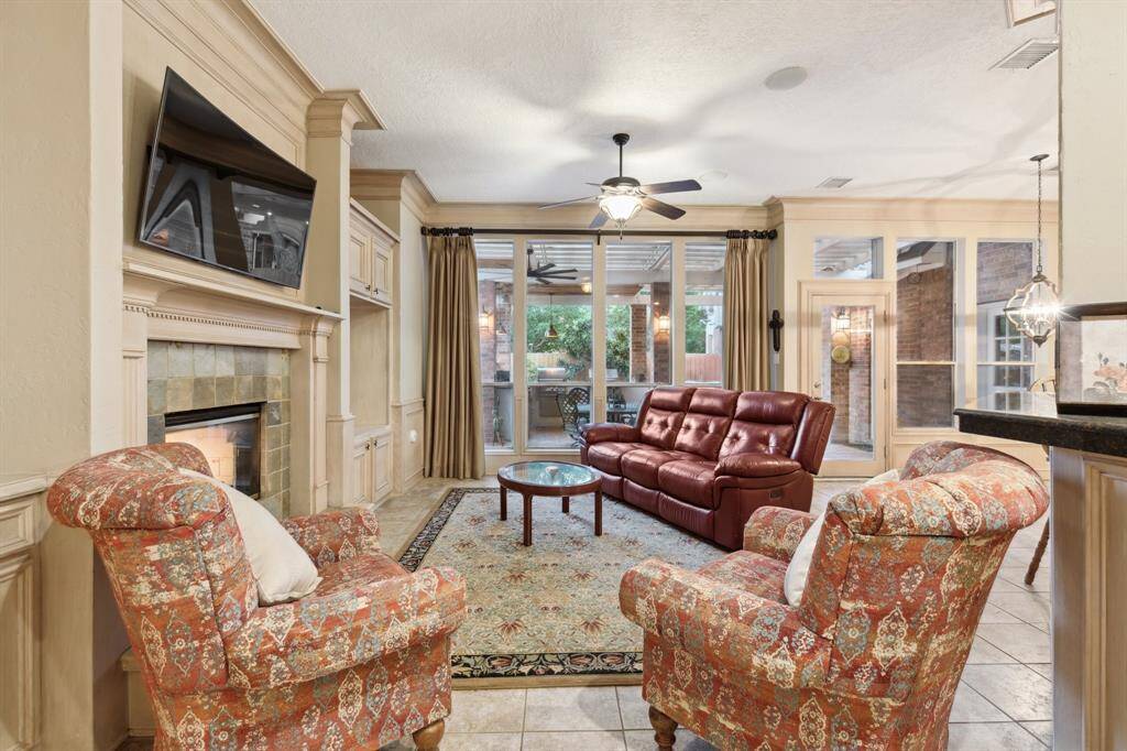 Cozy family space with built-ins and fireplace, connected to kitchen and patio.