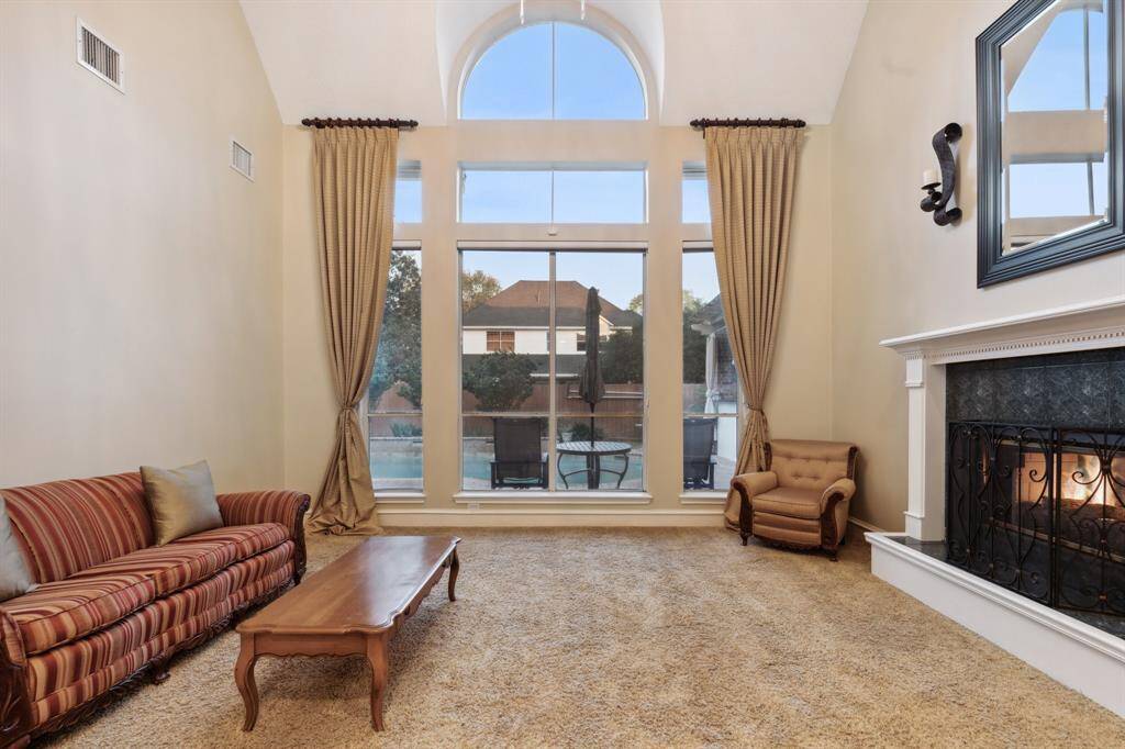 Bright formal living with soaring ceilings and large arched window.