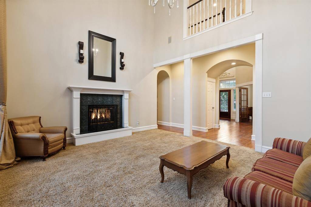Grand living area with two-story ceilings and central fireplace.