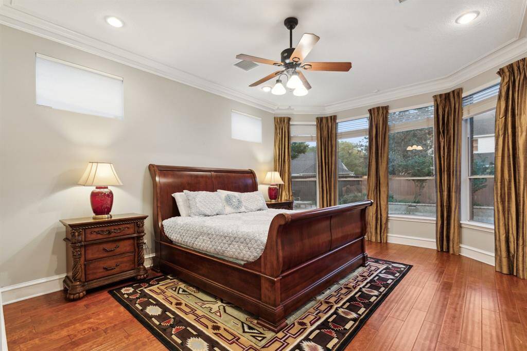 Elegant primary suite with wood flooring, curved window wall, and serene views.