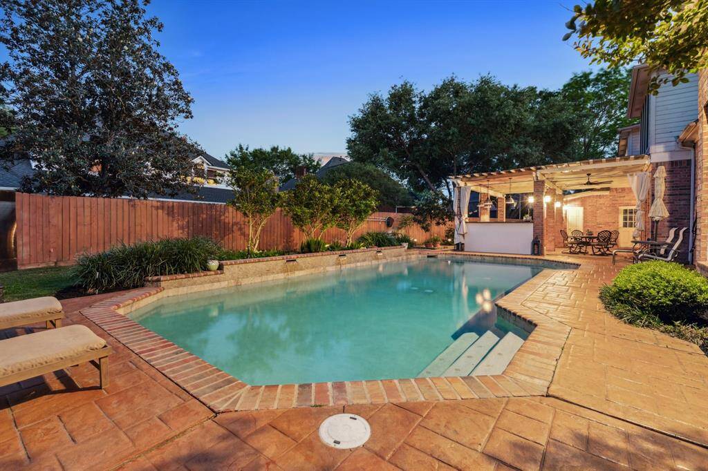 Tranquil pool with easy-entry steps and privacy landscaping, perfect for evening swims.