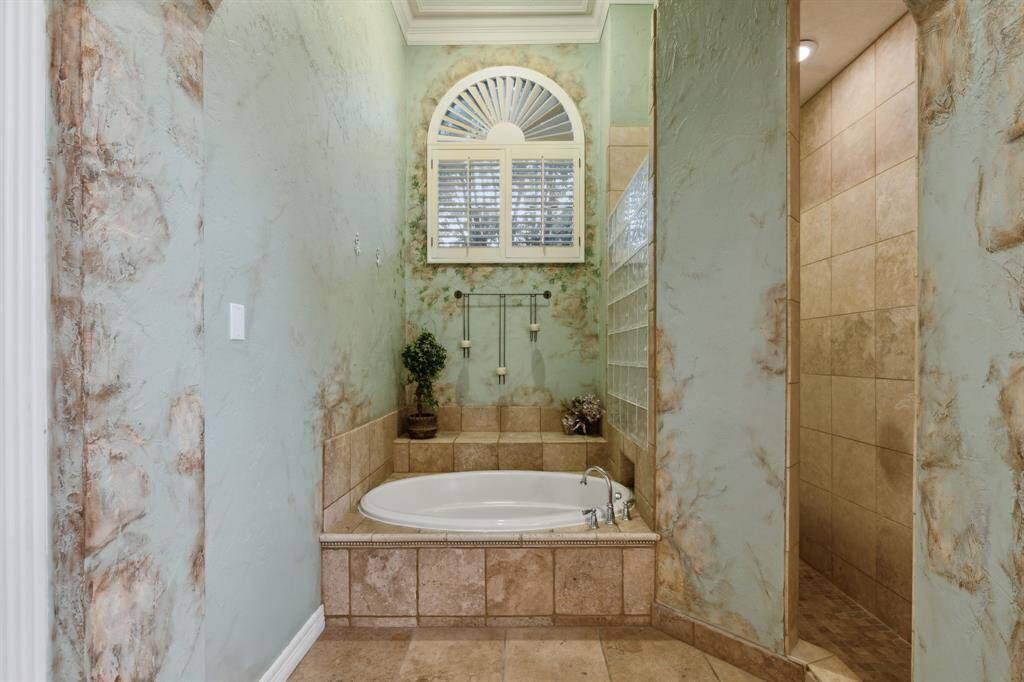 Arch-framed jetted tub and walk-in shower in a spa-like setting.