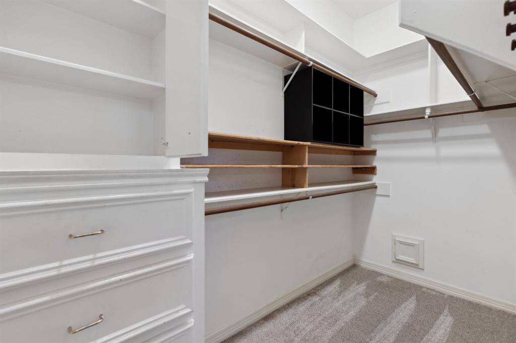 Generous walk-in closet with custom shelving and built-in drawers.