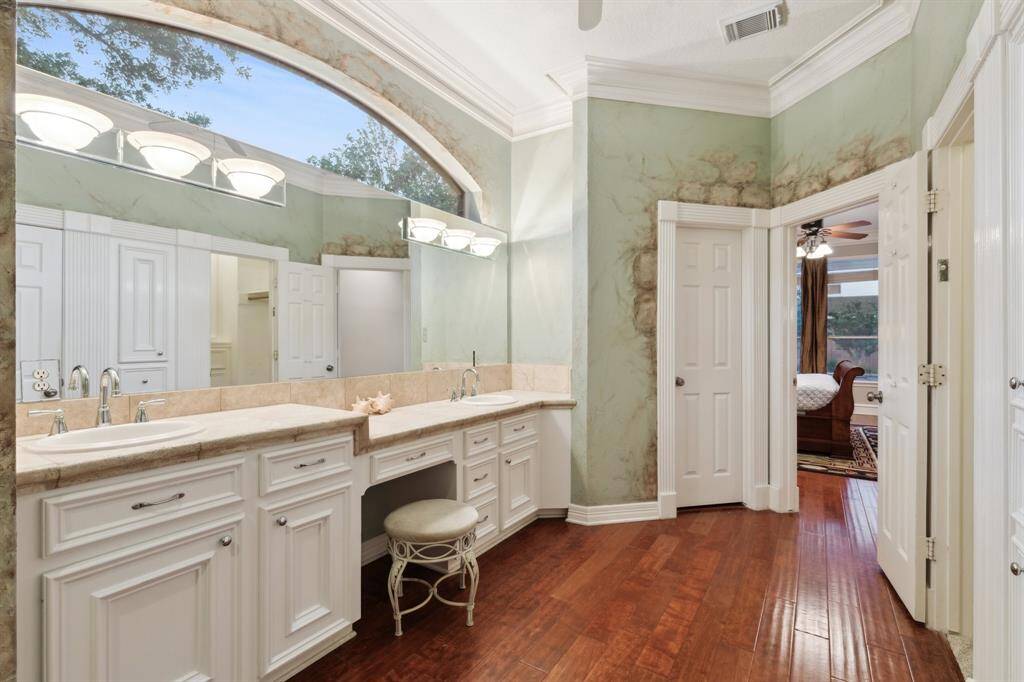 Wide view of the luxurious bath showcasing dual vanities and arched window.