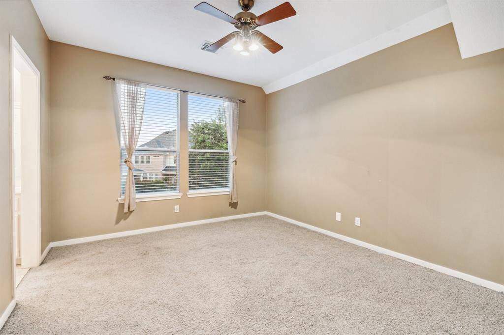Sunny secondary bedroom with large window and neutral carpet.