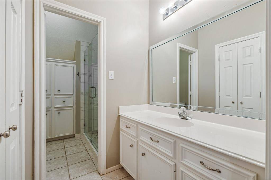 Bright full bath with extended vanity and glass-enclosed shower.