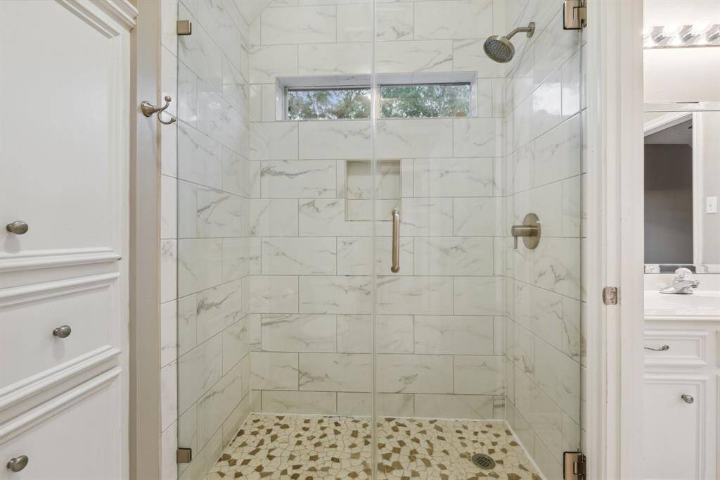 Walk-in shower with tile walls, pebbled floor, and built-in niche.