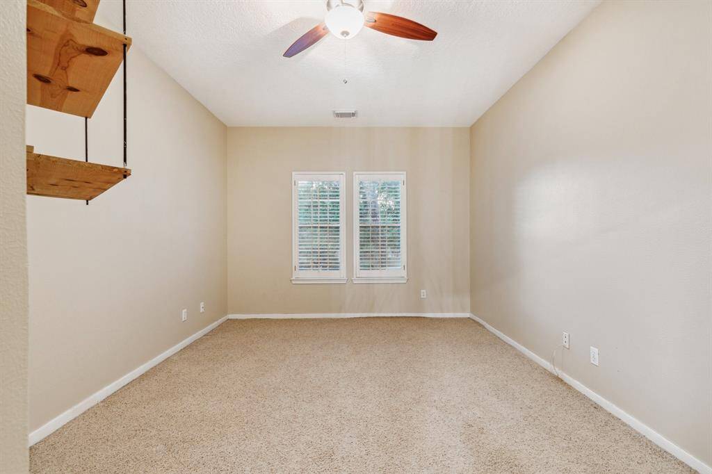 Cozy carpeted bedroom with twin windows and neutral paint.
