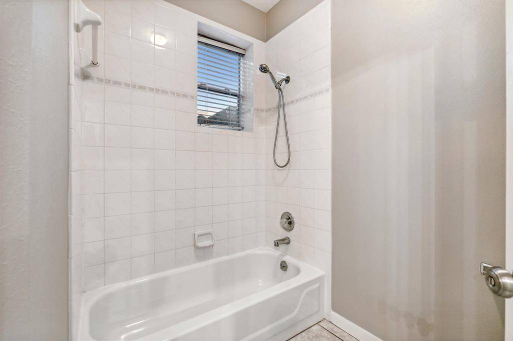 White tile shower-tub combo with window above for natural light.