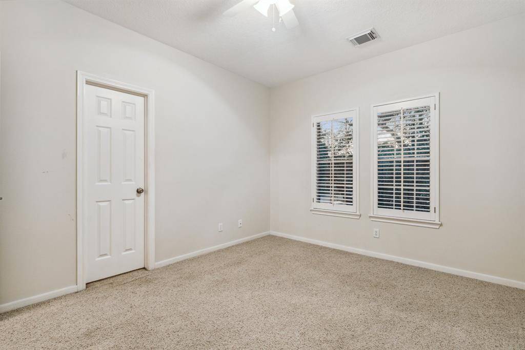 Carpeted secondary bedroom with two windows and ceiling fan.