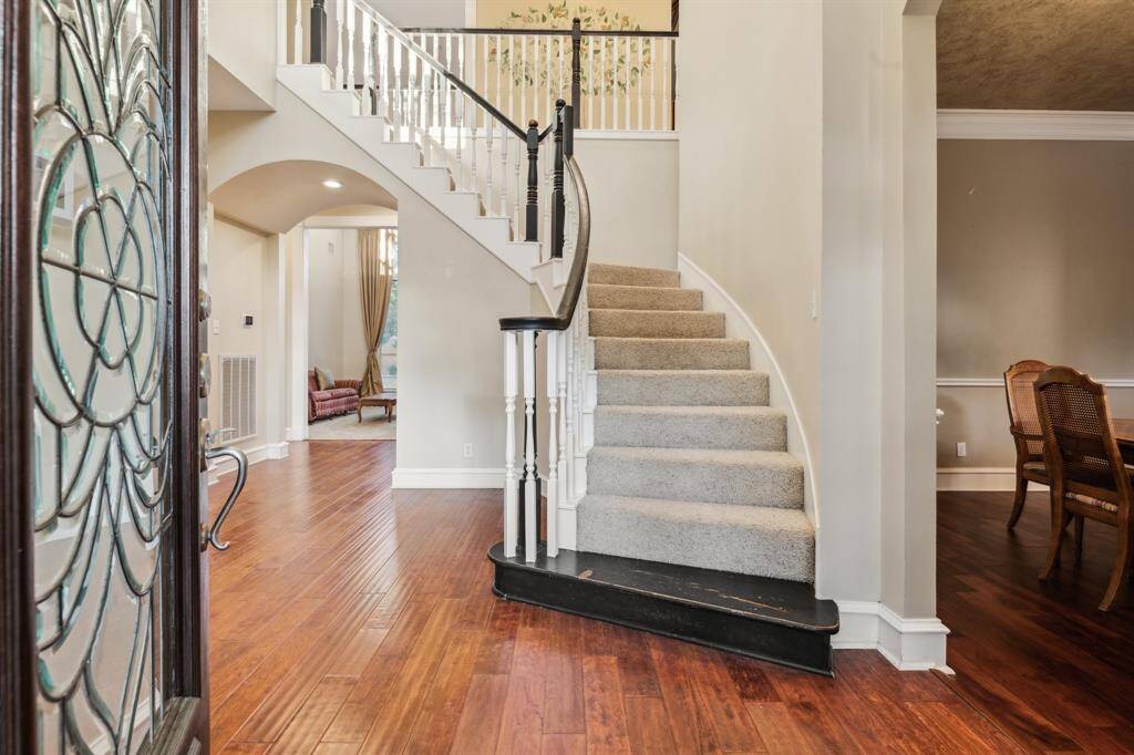 Grand entry with sweeping staircase and elegant arched openings.