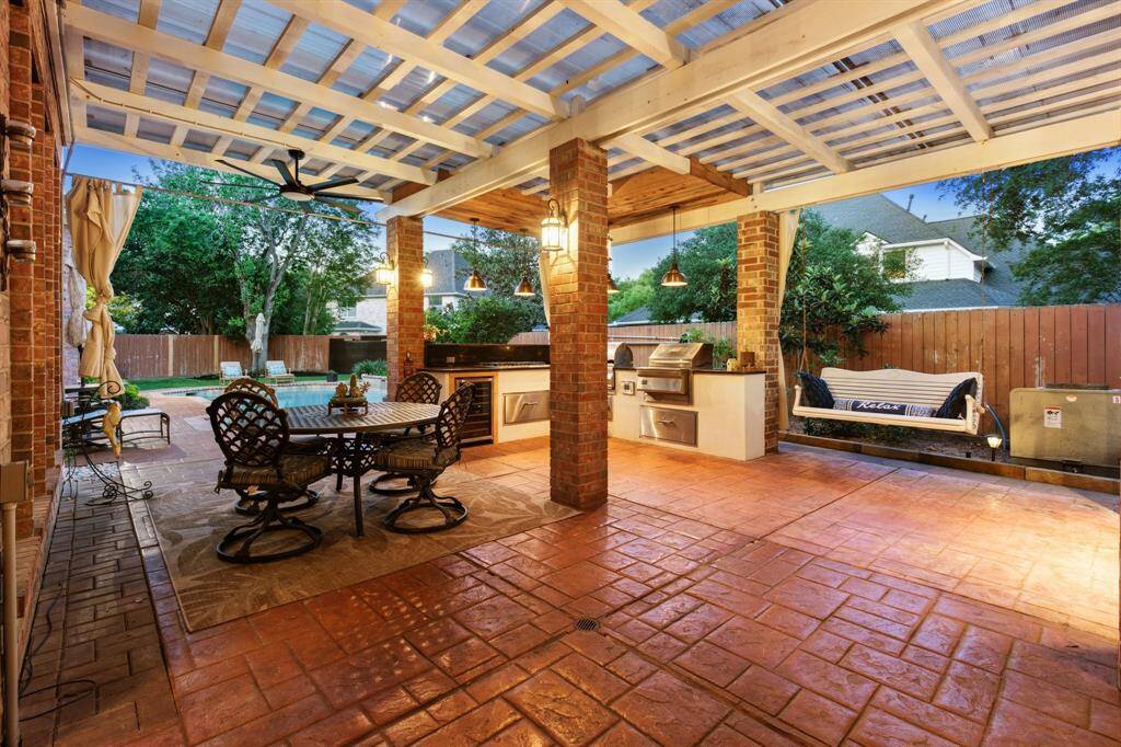 Spacious outdoor kitchen and dining space under a pergola, perfect for entertaining.