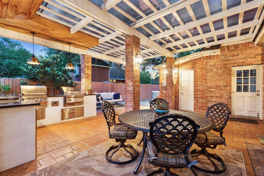 Charming evening dining setup with pergola cover and grilling station.
