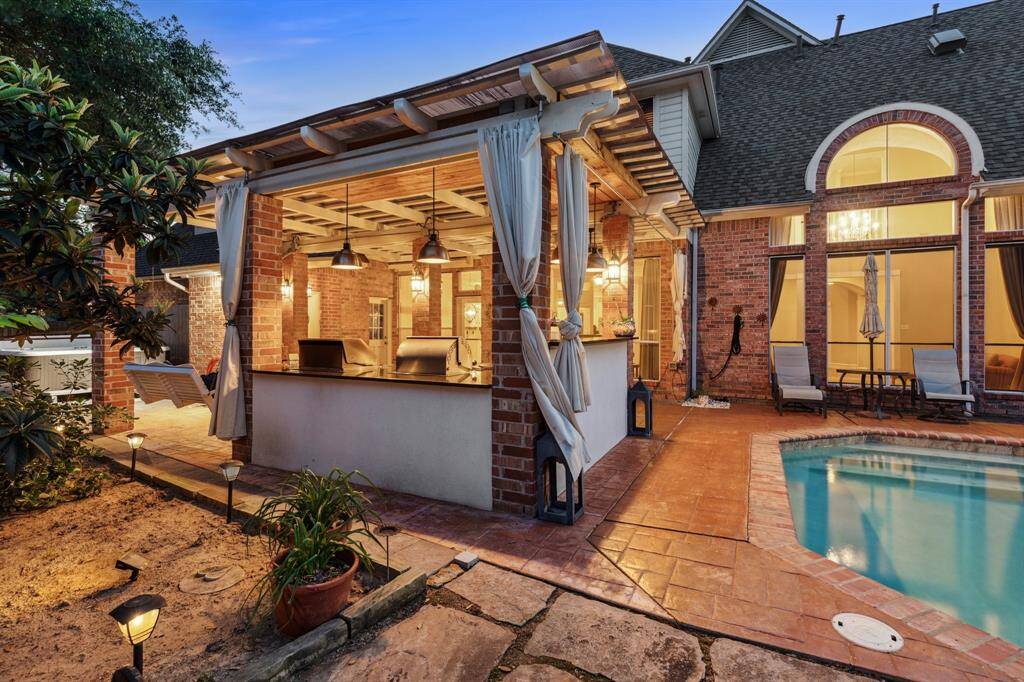 Covered outdoor kitchen with direct poolside access, lit perfectly for evening relaxation.