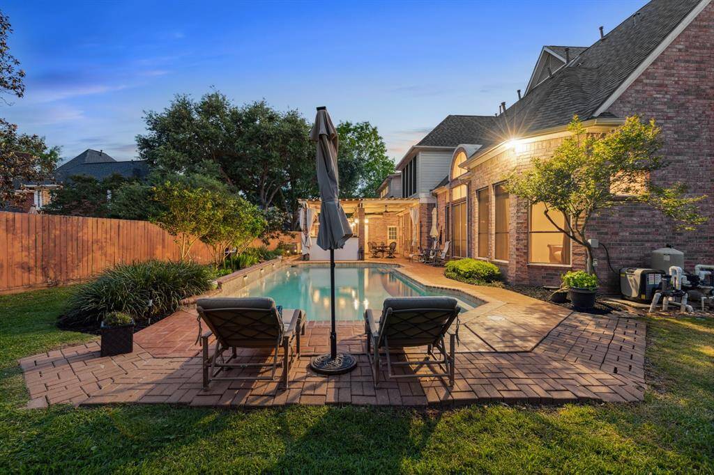 Serene poolside lounge setup, framed by greenery and ambient lighting at dusk.