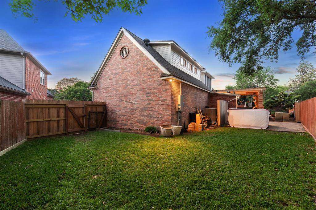 Spacious fenced backyard with a peaceful twilight setting and hot tub corner.