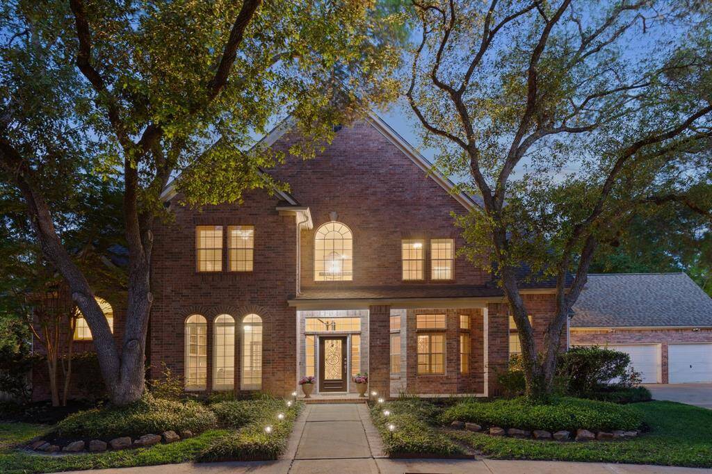 Welcoming front elevation at 23007 Meadow Pond Cir, framed by mature trees and soft light.