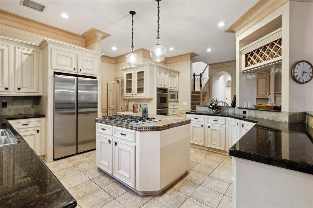 Center island with gas cooktop, double ovens, and custom cabinetry.