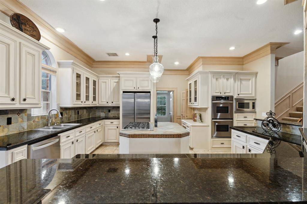 Wall-to-wall cabinets, built-in fridge, and pendant lighting.