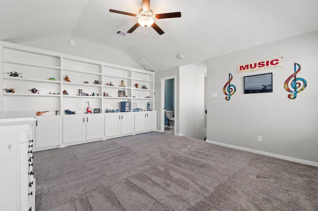 Game room upstairs with ceiling fans and custom built in shelves and cabinets