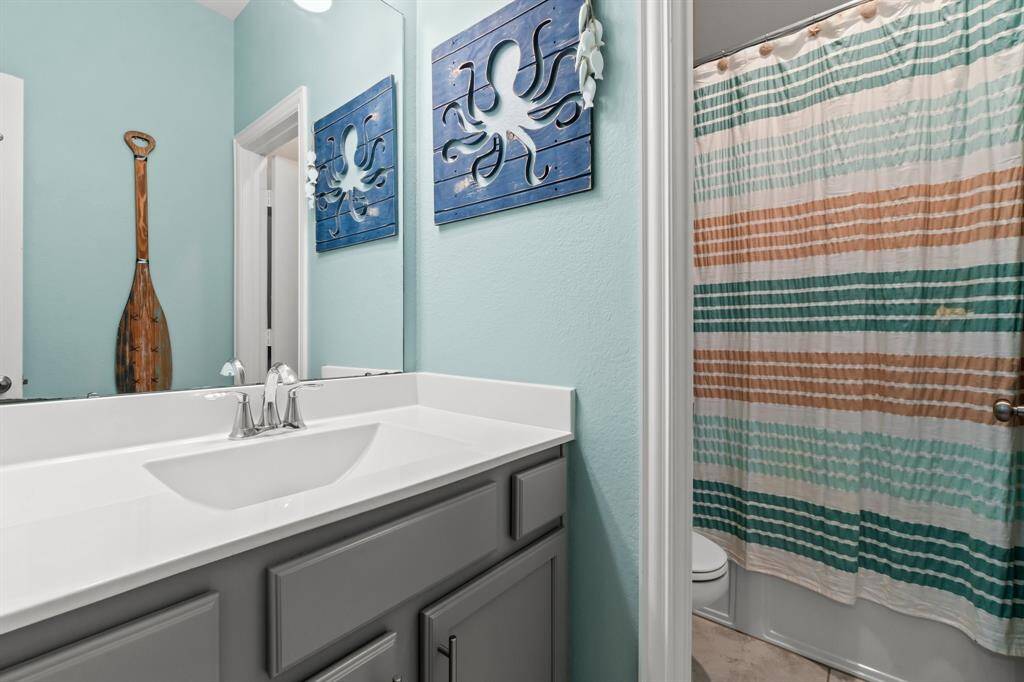 Secondary bathroom with hard wood cabinets and combination shower tub