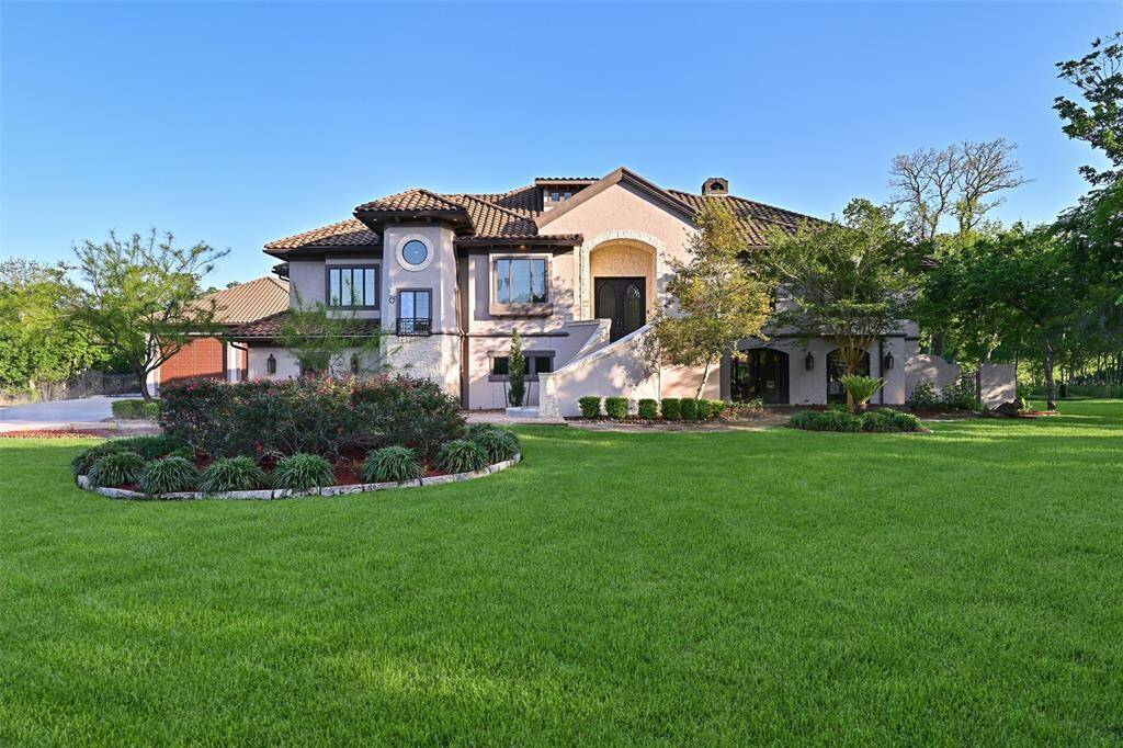 Daytime photos capture the beauty of the front lawn, extensive greenery and beautiful low-maintenance concrete and stone exterior with a Mediterranean flair.