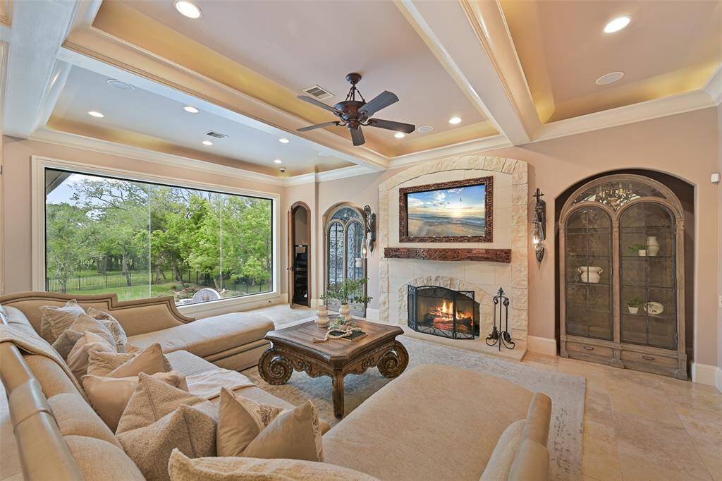 Unique & intriguing sconces flank each side of the fireplace and can be height adjusted by a pulley system. Extensive ceiling detailing, crown molding, limestone flooring and views outdoors make the living room a casual yet elevated space to enjoy.
