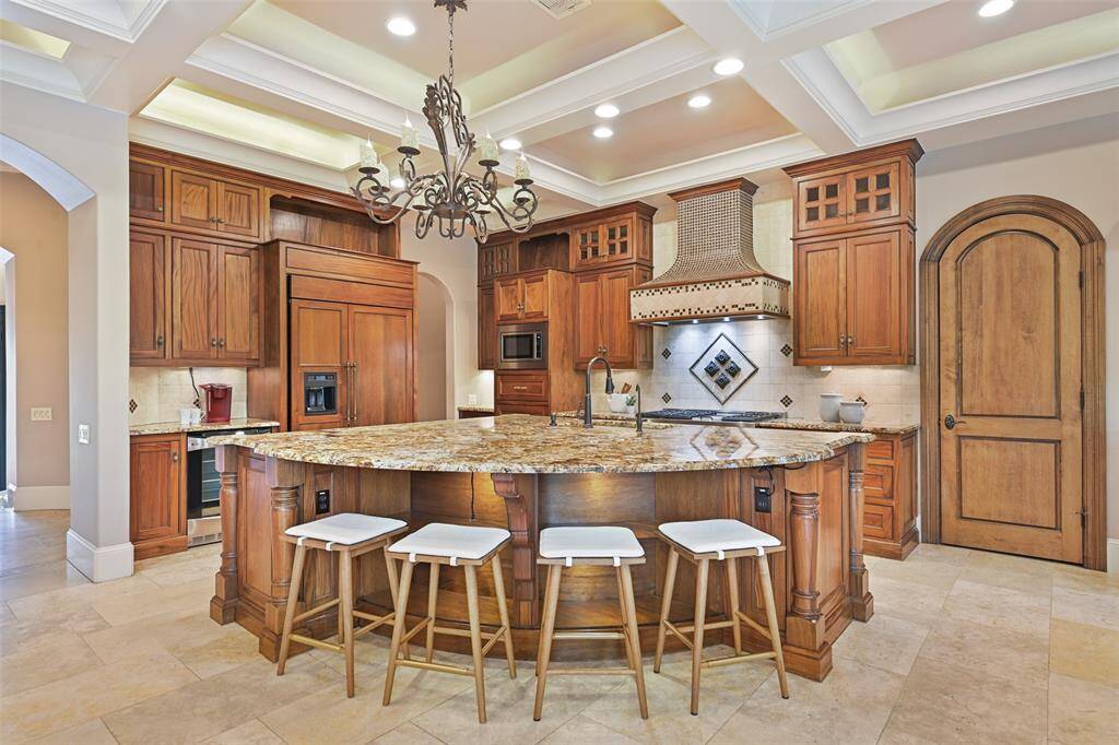 The gourmet kitchen adorns a huge island with breakfast bar, rich wood cabinetry, granite countertops and stone backsplash.