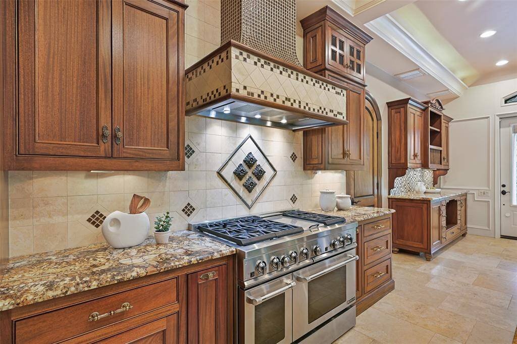 Another view of the gas range & gorgeous granite counters. To the right of the gas range, a large walk-in pantry is housed behind a beautiful solid wood door. Just beyond, is a built in antique furniture inspired built-in.