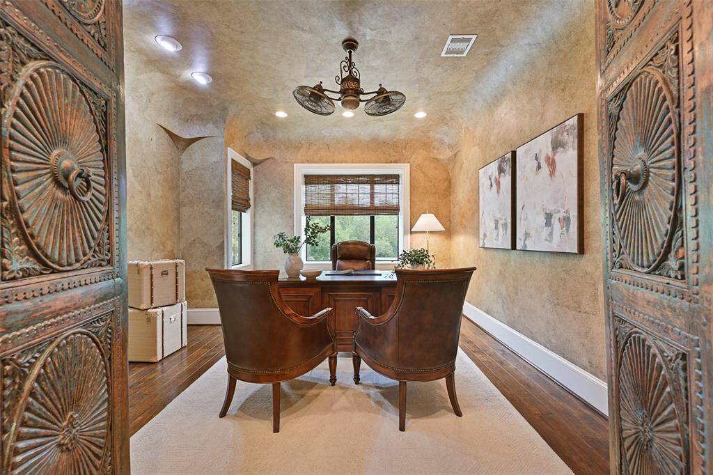 A private home office/study with hardwood floors, luxurious wall covering, and antique double doors.