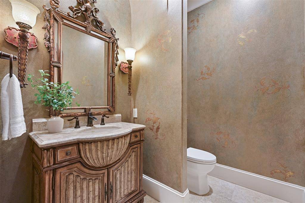 Located on the main 2nd floor of the home, an elegant half bath with bidet, beholds a marble & antique finished vanity showcased by soft sconce lighting & faux custom finished walls.