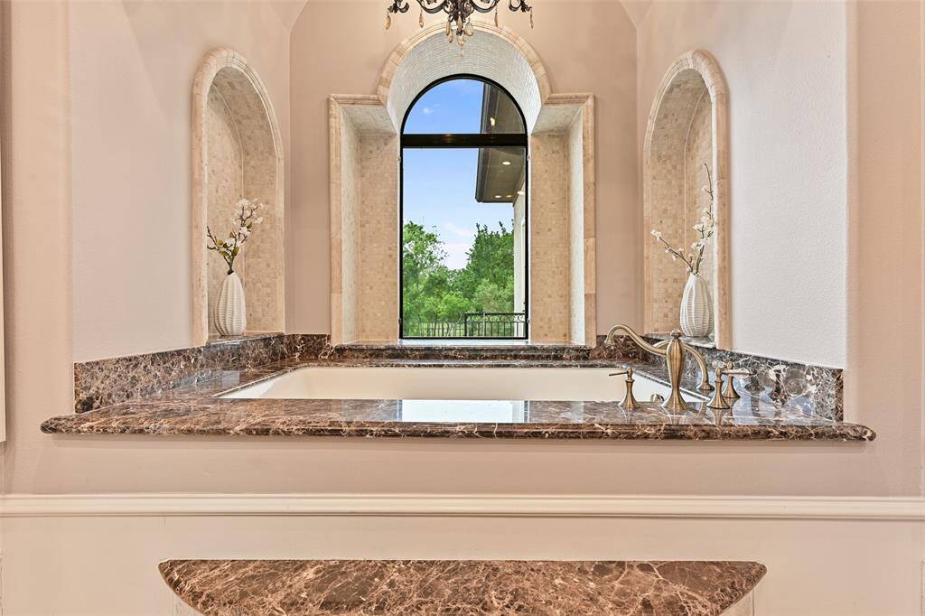 Beautiful tile & stone niches, elegant chandelier and dramatic views outdoors cast a spa-like setting from the large soaking tub.