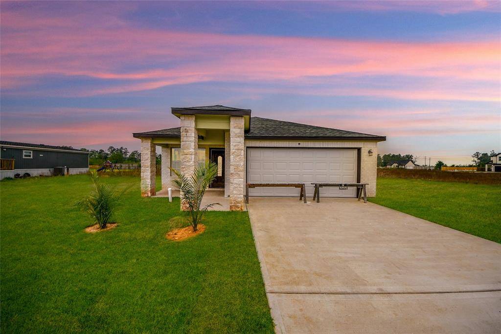 Stunning twilight shot capturing the home's warm exterior glow, enhanced by the vibrant sunset sky and professionally landscaped front yard.