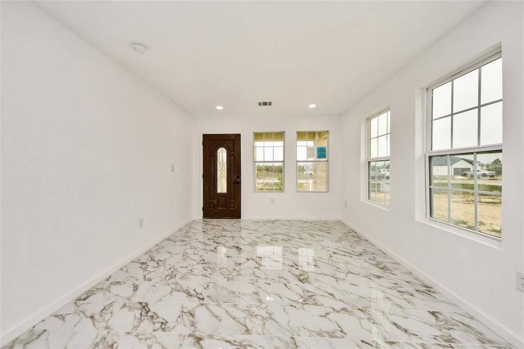 Welcoming entryway with large windows providing abundant natural light, marble-style flooring, and a beautiful wood-accented front door.