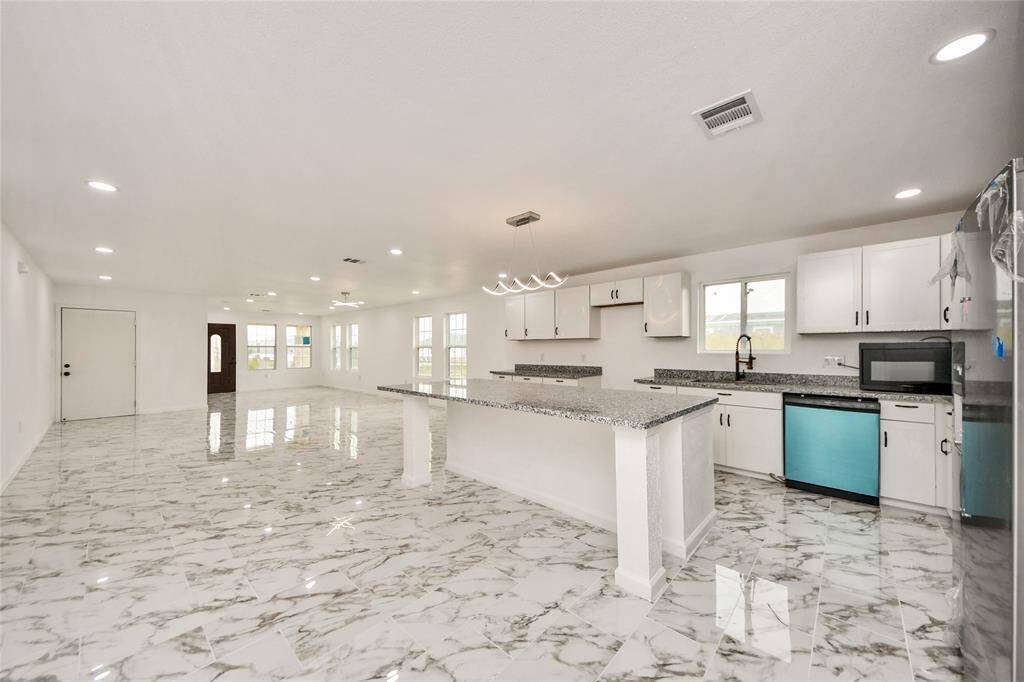 A wide-angle view from the kitchen showing the seamless transition to the bright, airy living and dining areas.