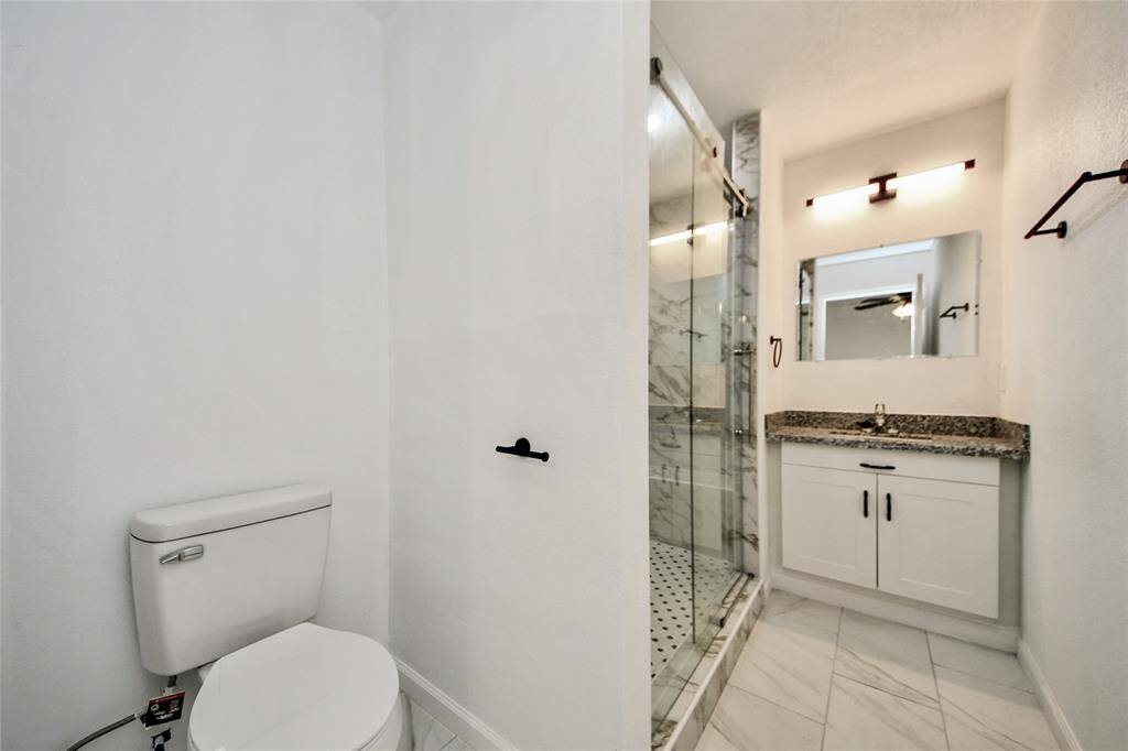 Elegant bathroom with a large vanity, granite countertop, modern lighting, and sleek black hardware.
