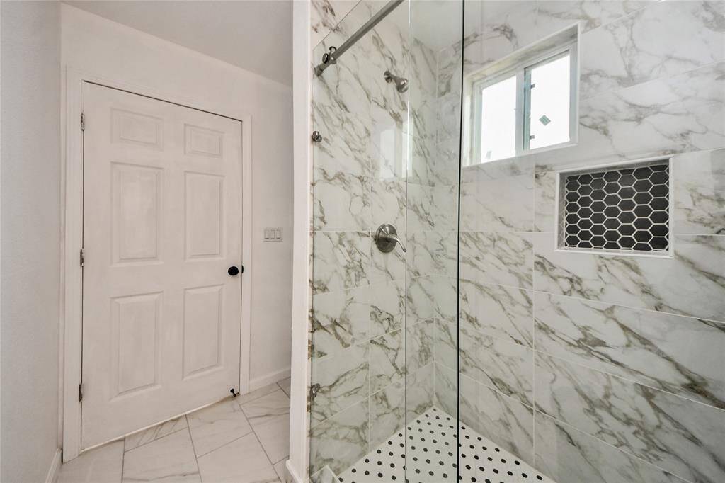 Another angle showcasing the spacious shower and the door leading back into the bedroom.