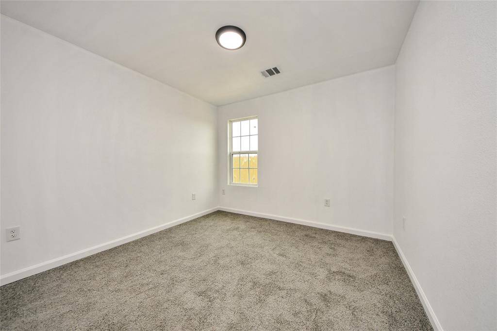 Bright and airy secondary bedroom featuring soft neutral tones, plush carpeting, and a large window bringing in abundant natural light.