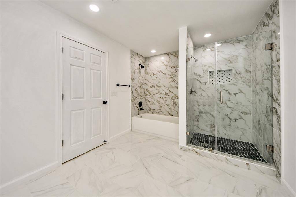 Elegant walk-in shower with frameless glass, designer tile, and a separate soaking tub creating a luxurious, spa-inspired experience.