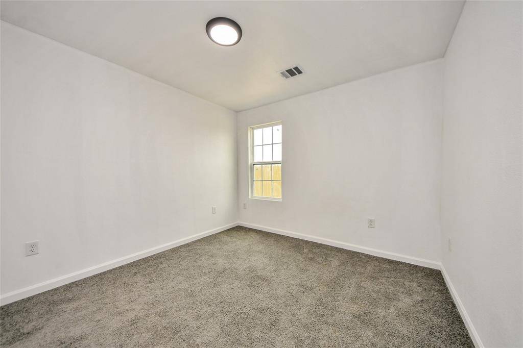 Another inviting secondary bedroom with soft carpeting, a bright window, and a neutral color scheme ready for personalization.