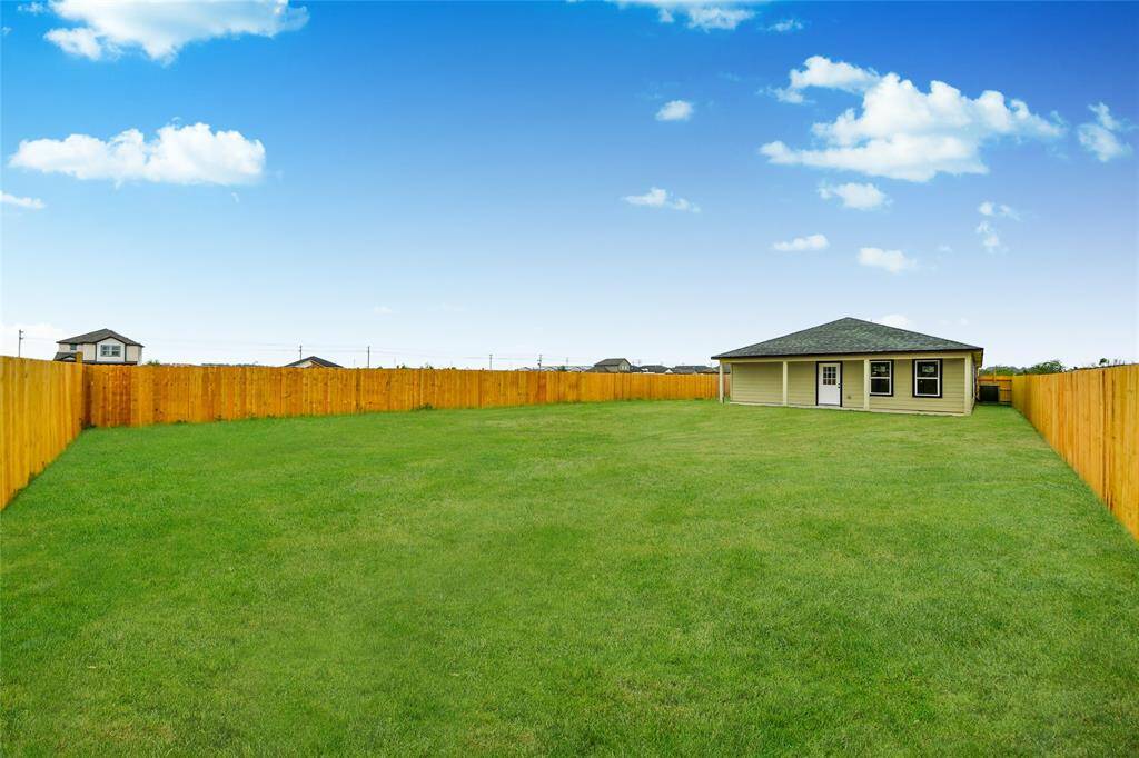 Full view of the home from the far end of the backyard, emphasizing the size of the lot and ample green space.