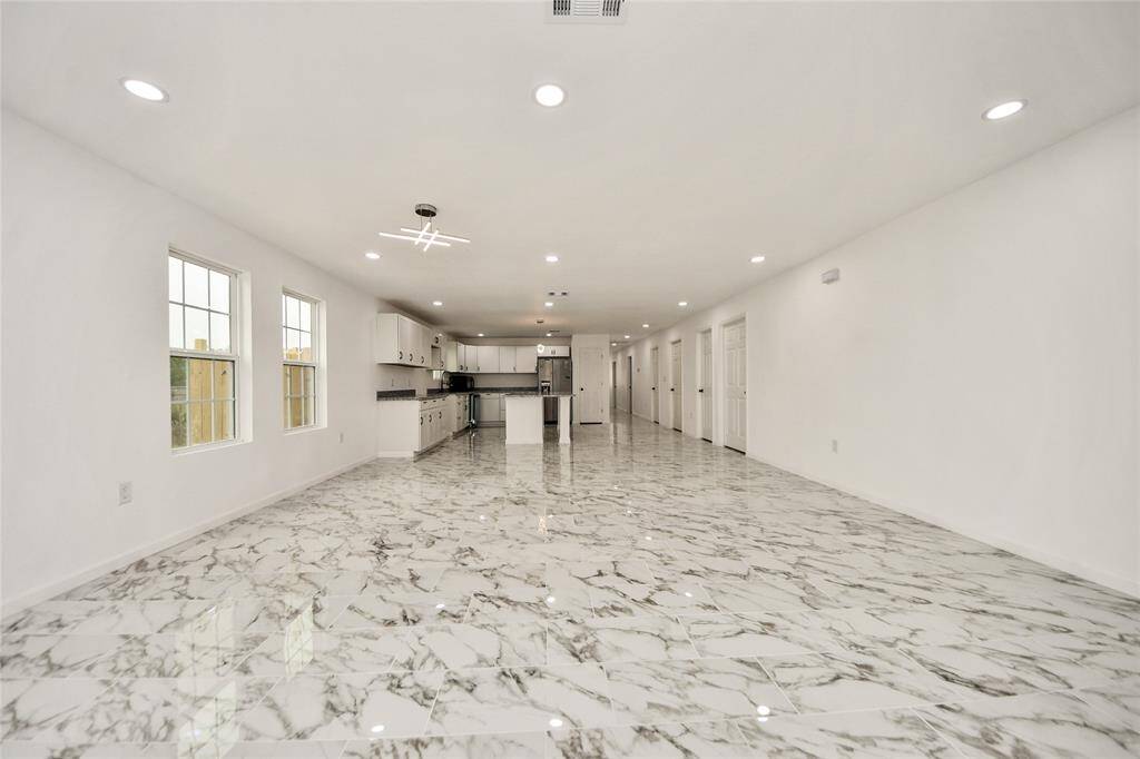 A full-width view of the expansive living and kitchen space, highlighting the natural light streaming through multiple windows and the cohesive contemporary design.