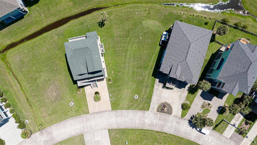 This direct aerial showcases how the curving road in front and delicate waterline behind elegantly frame the lot’s position.