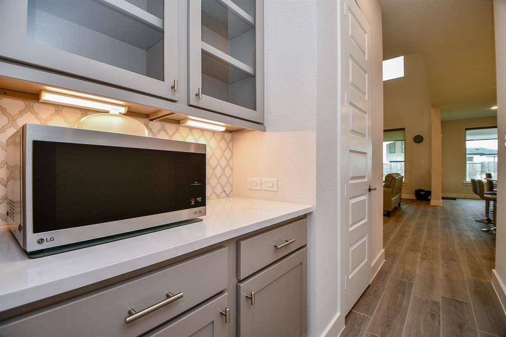 Butler pantry with quartz counter and glass cabinet