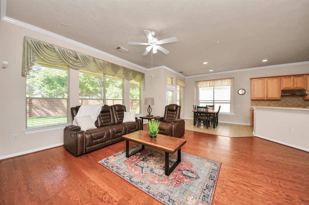This expansive living area seamlessly connects to the dining and kitchen spaces, creating an ideal setting for both entertaining and everyday living. Abundant natural light floods the room through large windows, enhancing the sense of space and warmth