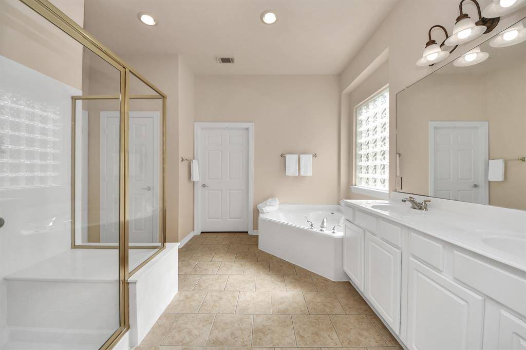 ndulge in luxury with this spa-inspired en-suite featuring a tranquil garden tub, separate glass-enclosed shower, and dual vanities. Elegant finishes and thoughtful design create a serene retreat for relaxation and rejuvenation