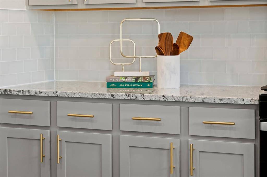 The granite countertop and backsplash is Taupe Grey, and the kitchen cabinets are Woodmont Dakota Shaker Panel with contemporary steel pull hardware in brushed gold.