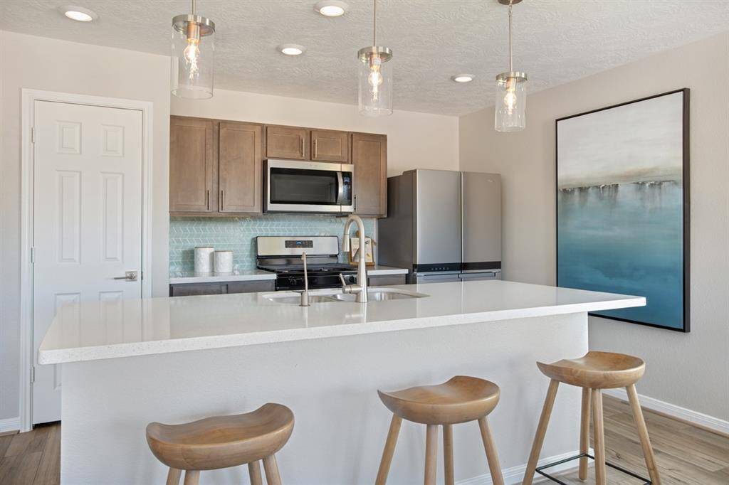 This kitchen will not disappoint! Your family and guests will enjoy many nights of fun, food and entertainment with ample counter space for setting up a wonderful array of provisions! The view of this gorgeous kitchen showcases the bright open kitchen with high ceiling, recessed lighting, pendant lighting, vinyl plank flooring, SS appliances, silestone countertops, kitchen island with extended countertop for breakfast bar, beautiful moder tile backsplash, and pantry!